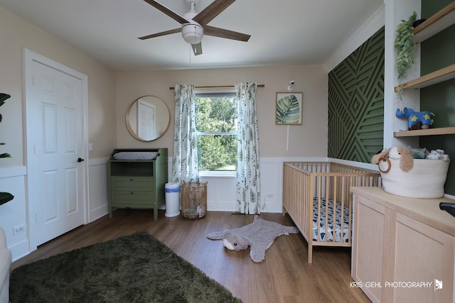 1115 E Fox Chase Dr, Round Lake Beach, IL 60073 - bedroom featuring a nursery area, wood finished floors, wainscoting, and a ceiling fan