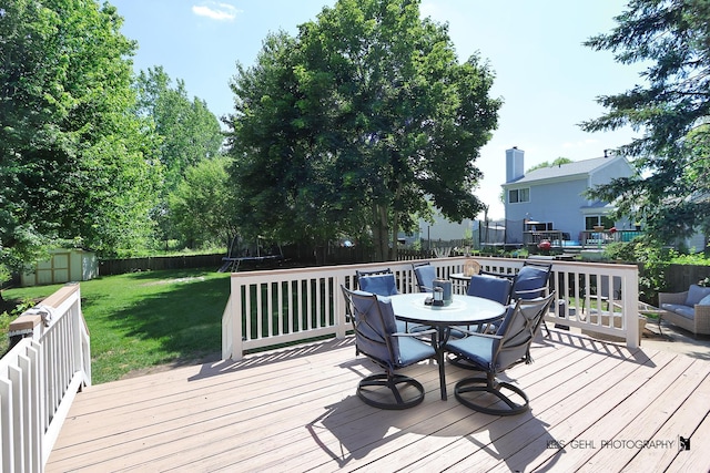 1115 E Fox Chase Dr, Round Lake Beach, IL 60073 - deck with a trampoline, outdoor dining space, a fenced backyard, and a storage unit
