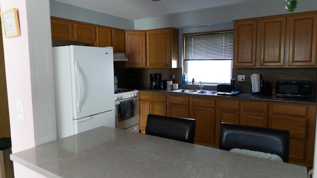 5704 W Montrose Ave Unit 2B, Chicago, IL 60634 - kitchen with white appliances, under cabinet range hood, brown cabinets, and tasteful backsplash