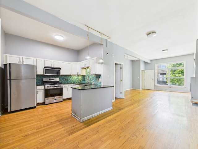 2933 W Wilcox St, Chicago, IL 60612 - kitchen featuring stainless steel appliances, dark countertops, white cabinetry, backsplash, and light wood-type flooring