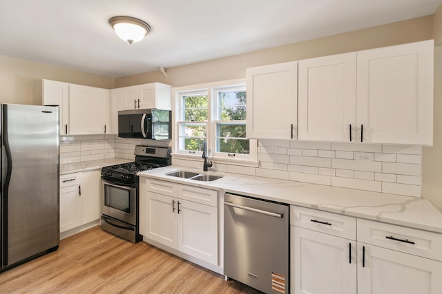 14348 Knox Ave, Midlothian, IL 60445 - kitchen with appliances with stainless steel finishes, white cabinets, light stone counters, light wood finished floors, and backsplash
