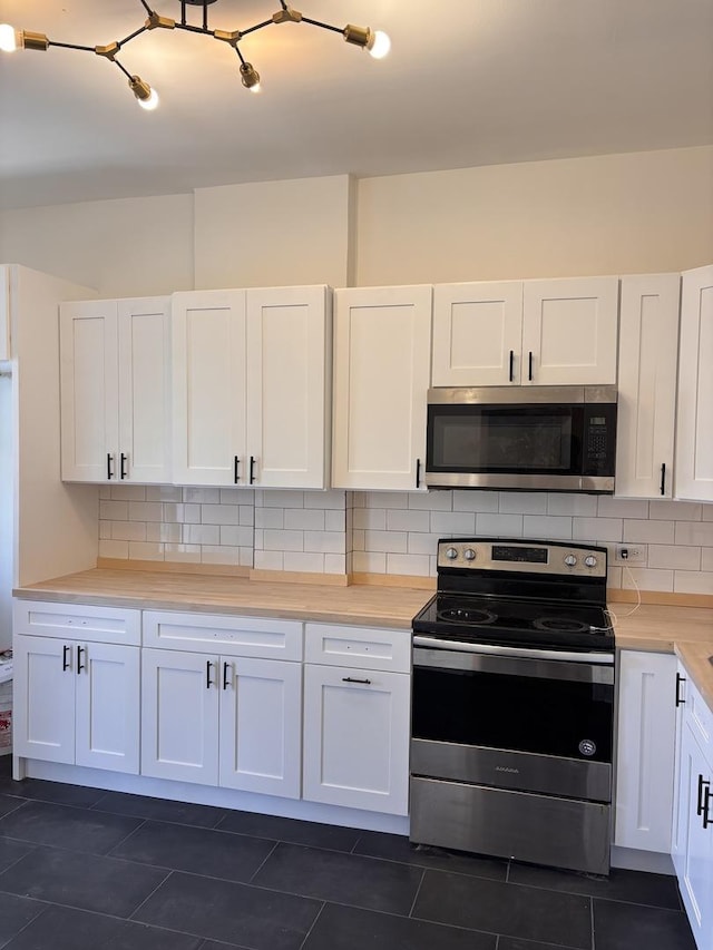 4138 W Adams St, Chicago, IL 60624 - kitchen featuring stainless steel appliances, white cabinetry, dark tile patterned flooring, light countertops, and backsplash