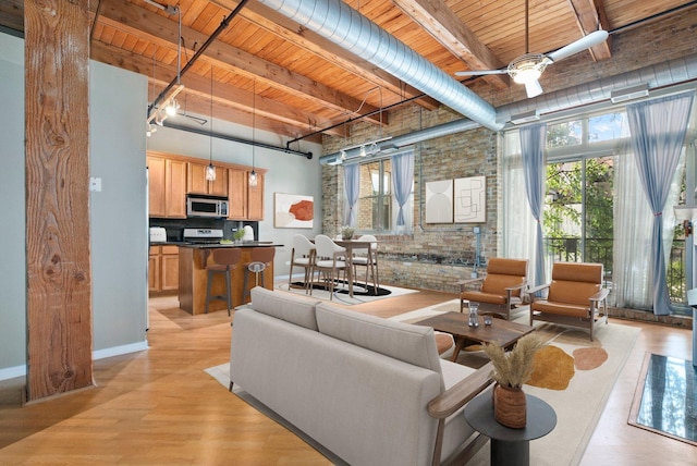 1740 N Maplewood Ave Unit 218, Chicago, IL 60647 - living room featuring a wooden ceiling with exposed beams, brick wall, a ceiling fan, light wood-style floors, and healthy amount of natural light