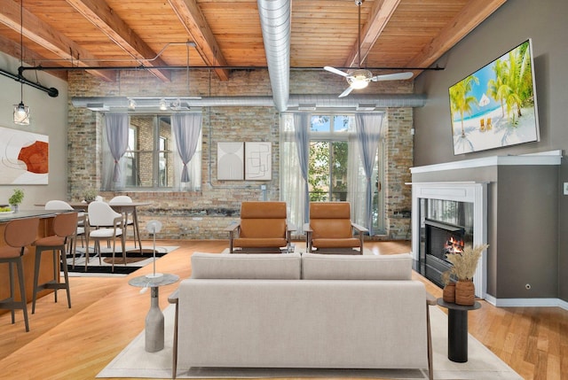 1740 N Maplewood Ave Unit 218, Chicago, IL 60647 - living room featuring a wooden ceiling with exposed beams, wood finished floors, a warm lit fireplace, and ceiling fan