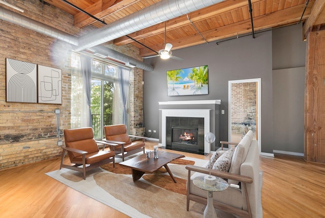 1740 N Maplewood Ave Unit 218, Chicago, IL 60647 - living room with a wood ceiling with exposed beams, brick wall, a lit fireplace, wood finished floors, and a ceiling fan