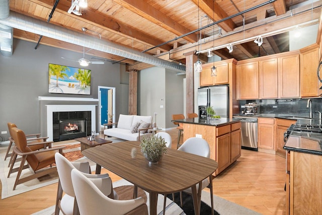 1740 N Maplewood Ave Unit 218, Chicago, IL 60647 - kitchen with a wood ceiling with exposed beams, stainless steel appliances, light wood-style flooring, dark countertops, and a kitchen island