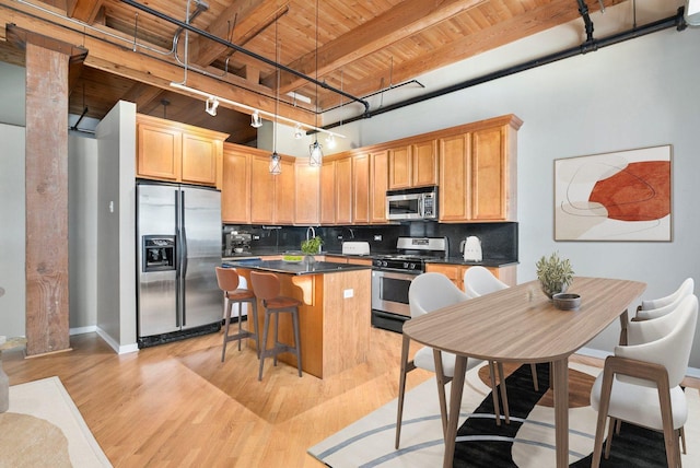 1740 N Maplewood Ave Unit 218, Chicago, IL 60647 - kitchen with appliances with stainless steel finishes, a wooden ceiling with exposed beams, a center island, light wood-style flooring, and dark countertops