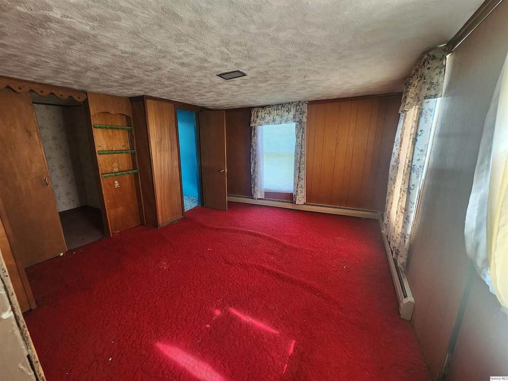 525 Chestnut, Quincy, IL 62301 - unfurnished bedroom with a baseboard radiator, carpet, wood walls, and a textured ceiling