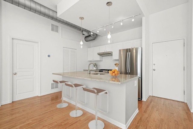 1645 W School St Unit 318, Chicago, IL 60657 - kitchen featuring freestanding refrigerator, under cabinet range hood, light wood-style floors, white cabinetry, and decorative backsplash