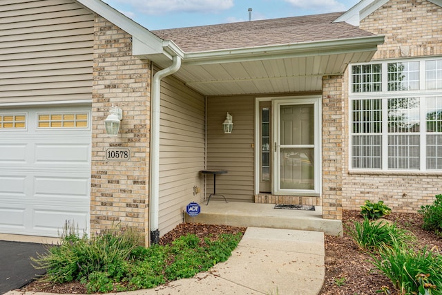 10578 Harrison Ct, Roscoe, IL 61073 - doorway to property featuring an attached garage, brick siding, a shingled roof, and covered porch