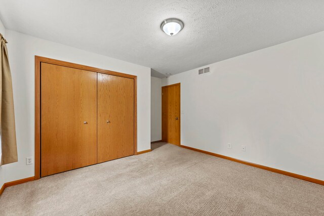 10578 Harrison Ct, Roscoe, IL 61073 - unfurnished bedroom with light carpet, a closet, and a textured ceiling