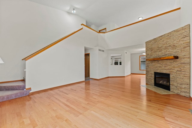 10578 Harrison Ct, Roscoe, IL 61073 - unfurnished living room with stairway, lofted ceiling, light wood-style flooring, and a stone fireplace