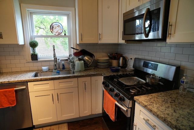 3321 W 71st St, Chicago, IL 60629 - kitchen featuring appliances with stainless steel finishes, white cabinetry, decorative backsplash, light stone countertops, and dark wood-style floors