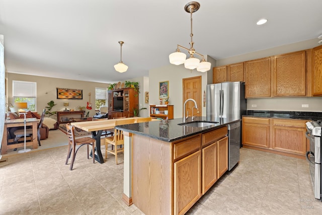 365 Oakmont Dr, Cary, IL 60013 - kitchen featuring appliances with stainless steel finishes, dark stone countertops, decorative light fixtures, a center island with sink, and light tile patterned flooring