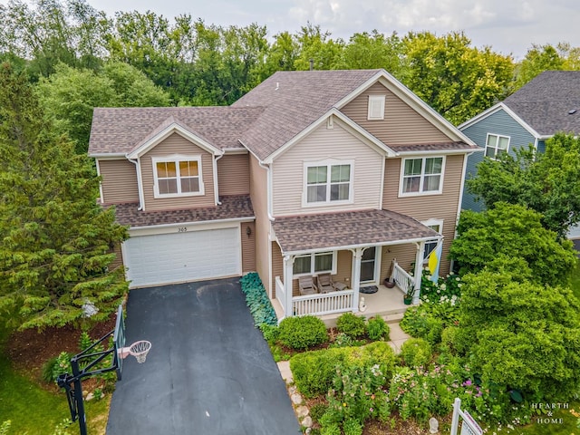 365 Oakmont Dr, Cary, IL 60013 - view of front of house with a porch, driveway, an attached garage, roof with shingles, and view of wooded area