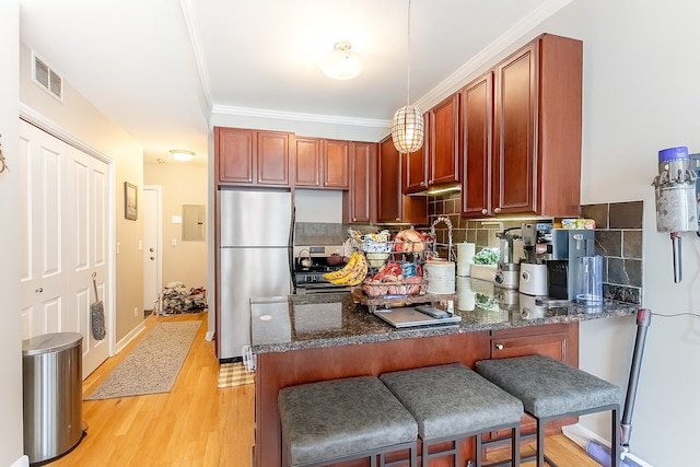 2716 N Kedzie Ave Unit 2, Chicago, IL 60647 - kitchen with freestanding refrigerator, light wood finished floors, dark stone countertops, a peninsula, and a kitchen bar