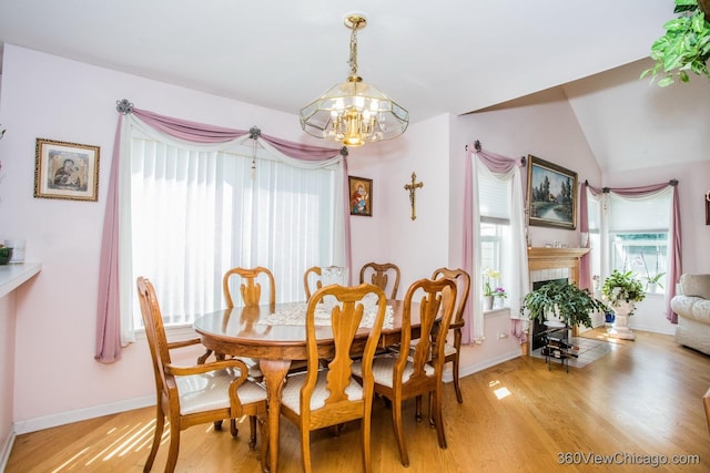 2325 N Lenox Ct, Round Lake Beach, IL 60073 - dining space with a chandelier, light wood-style flooring, a tiled fireplace, and lofted ceiling