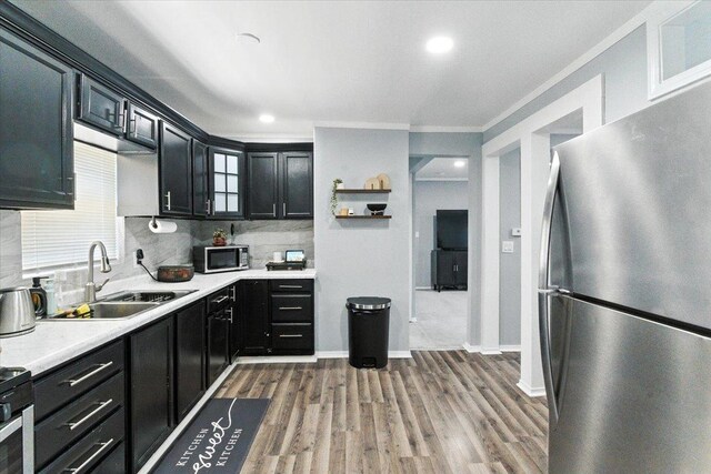 1518 Lucia Ave, Waukegan, IL 60085 - kitchen featuring stainless steel appliances, dark cabinetry, light countertops, wood finished floors, and backsplash