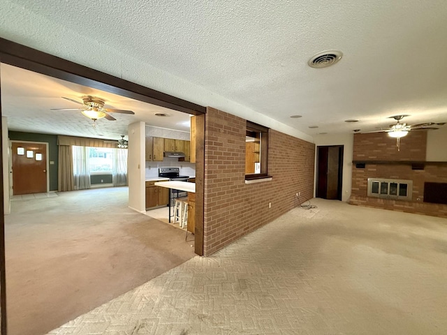 1340 Jeffrey Dr, Rantoul, IL 61866 - unfurnished living room with ceiling fan, light colored carpet, brick wall, a textured ceiling, and a brick fireplace