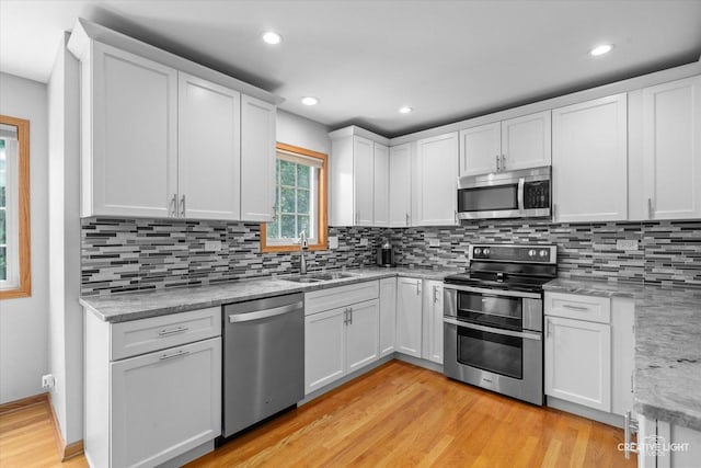 210 Fox Chase Dr N, Oswego, IL 60543 - kitchen with stainless steel appliances, light wood-style flooring, white cabinetry, decorative backsplash, and light stone counters