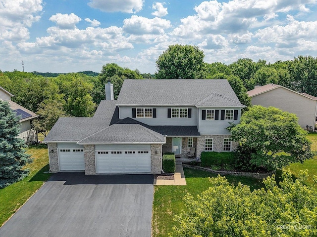 210 Fox Chase Dr N, Oswego, IL 60543 - view of front of property with a garage, asphalt driveway, a chimney, a front yard, and brick siding