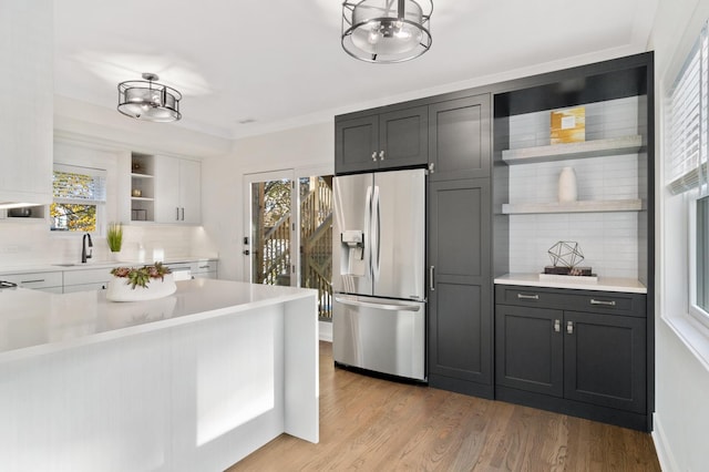 1116 W Addison St, Chicago, IL 60613 - kitchen with stainless steel fridge with ice dispenser, open shelves, backsplash, light countertops, and light wood finished floors