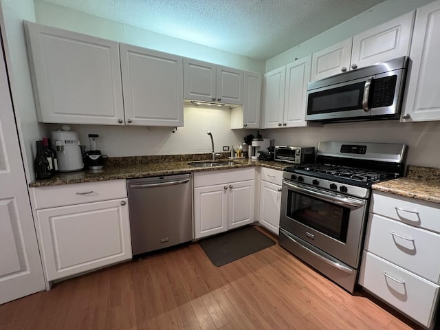 230 E Ontario St Unit 905, Chicago, IL 60611 - kitchen with appliances with stainless steel finishes, light wood-style floors, white cabinetry, a textured ceiling, and dark stone countertops