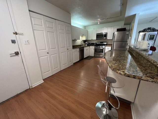 230 E Ontario St Unit 905, Chicago, IL 60611 - kitchen with stainless steel appliances, dark wood finished floors, white cabinets, and dark stone countertops