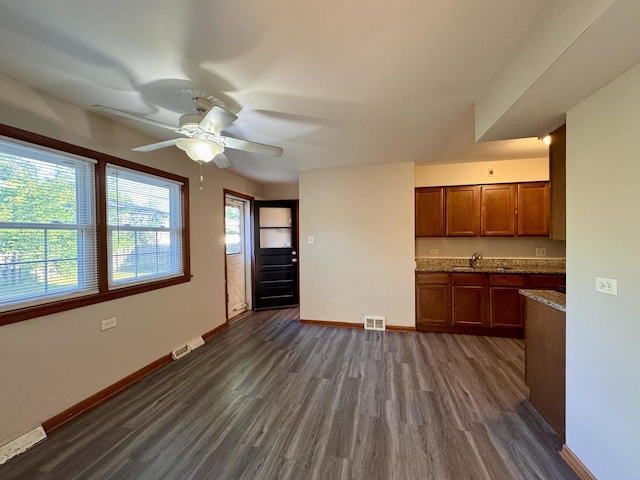 16850 School St, South Holland, IL 60473 - kitchen with dark wood-type flooring, brown cabinetry, ceiling fan, and dark stone counters