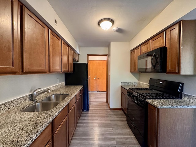 16850 School St, South Holland, IL 60473 - kitchen with black appliances, wood finished floors, dark stone counters, and brown cabinetry