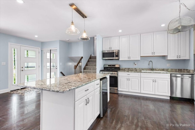 3920 Greenbay Dr, Hanover Park, IL 60133 - kitchen with appliances with stainless steel finishes, dark wood-style floors, light stone countertops, decorative light fixtures, and white cabinetry