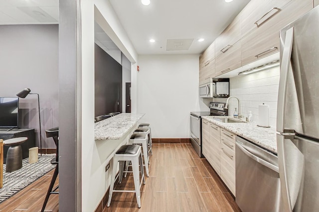 645 N Kingsbury St Unit 2002, Chicago, IL 60654 - kitchen featuring stainless steel appliances, modern cabinets, wood finish floors, a breakfast bar, and recessed lighting