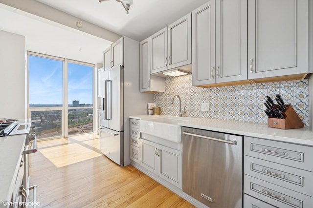 645 N Kingsbury St Unit 2002, Chicago, IL 60654 - kitchen with stainless steel appliances, backsplash, light wood-style floors, and light countertops