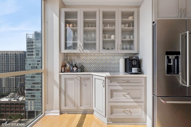 645 N Kingsbury St Unit 2002, Chicago, IL 60654 - kitchen with stainless steel fridge, glass insert cabinets, light wood finished floors, decorative backsplash, and light countertops