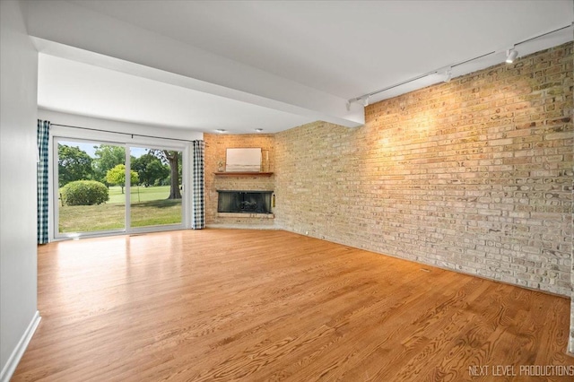 208 Kenston Ct Unit 208, Geneva, IL 60134 - unfurnished living room featuring track lighting, wood finished floors, brick wall, and a fireplace