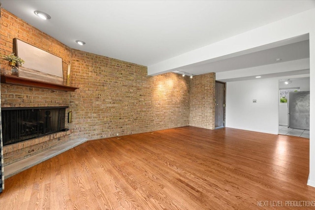 208 Kenston Ct Unit 208, Geneva, IL 60134 - unfurnished living room featuring wood finished floors, a fireplace, and brick wall