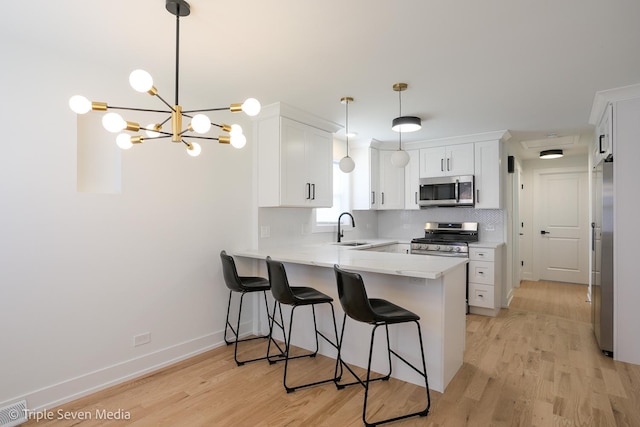 7939 Neva Ave, Burbank, IL 60459 - kitchen featuring stainless steel appliances, a peninsula, light wood-style flooring, white cabinets, and a kitchen breakfast bar