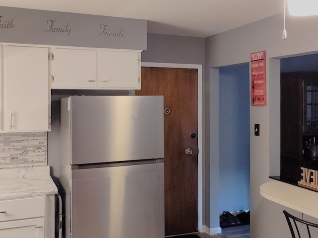 kitchen with freestanding refrigerator, tasteful backsplash, light countertops, and white cabinetry
