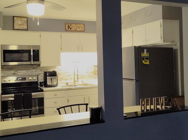 kitchen featuring stainless steel appliances, tasteful backsplash, white cabinets, and a ceiling fan