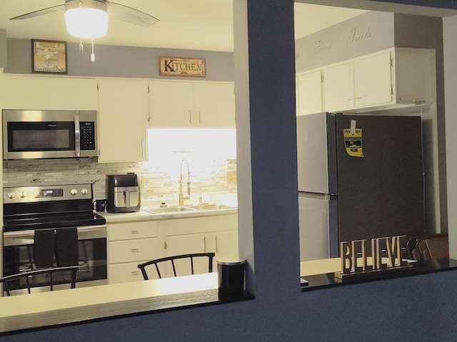 kitchen featuring appliances with stainless steel finishes, decorative backsplash, white cabinets, and ceiling fan