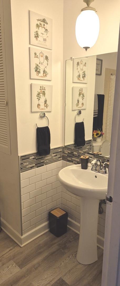 bathroom featuring wood finished floors, tile walls, and a wainscoted wall