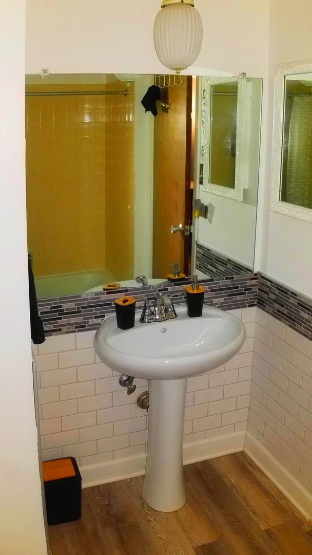 bathroom with wood finished floors and tile walls