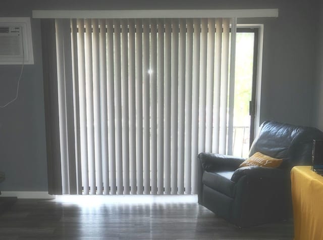 sitting room featuring an AC wall unit and wood finished floors