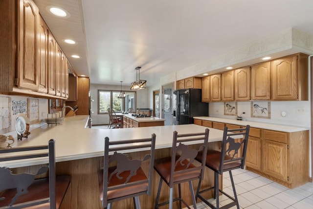 41W072 Bowes Rd, Elgin, IL 60124 - kitchen featuring black fridge, a peninsula, light countertops, a breakfast bar, and recessed lighting