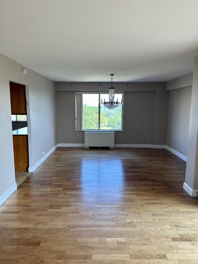 7033 N Kedzie Ave Unit 701, Chicago, IL 60645 - unfurnished room with radiator, a chandelier, and light wood-type flooring