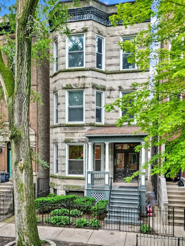 3516 N Reta Ave, Chicago, IL 60657 - view of front of house with stone siding, covered porch, a fenced front yard, and a gate