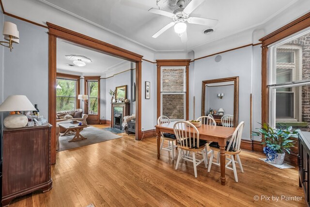 3516 N Reta Ave, Chicago, IL 60657 - dining space with light wood finished floors, crown molding, ceiling fan, and a fireplace with flush hearth