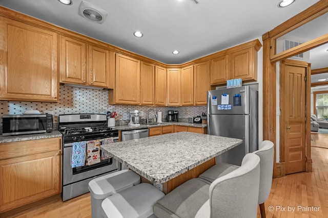 3516 N Reta Ave, Chicago, IL 60657 - kitchen featuring stainless steel appliances, light wood-style flooring, a breakfast bar, recessed lighting, and backsplash