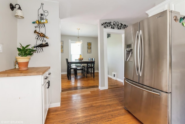 609 N 7th St, Dekalb, IL 60115 - kitchen featuring stainless steel refrigerator with ice dispenser, light wood-style flooring, white cabinets, wooden counters, and decorative light fixtures