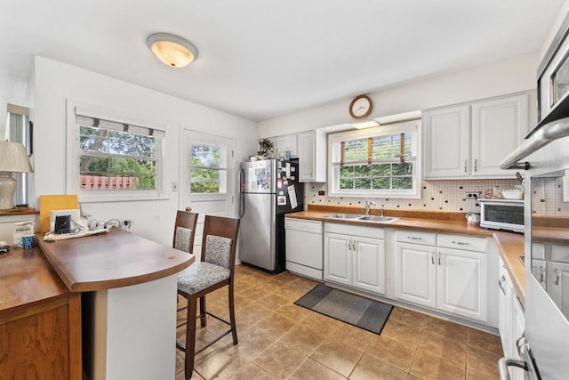 1207 W Busse Ave, Mount Prospect, IL 60056 - kitchen featuring dishwasher, freestanding refrigerator, a breakfast bar, white cabinetry, and backsplash
